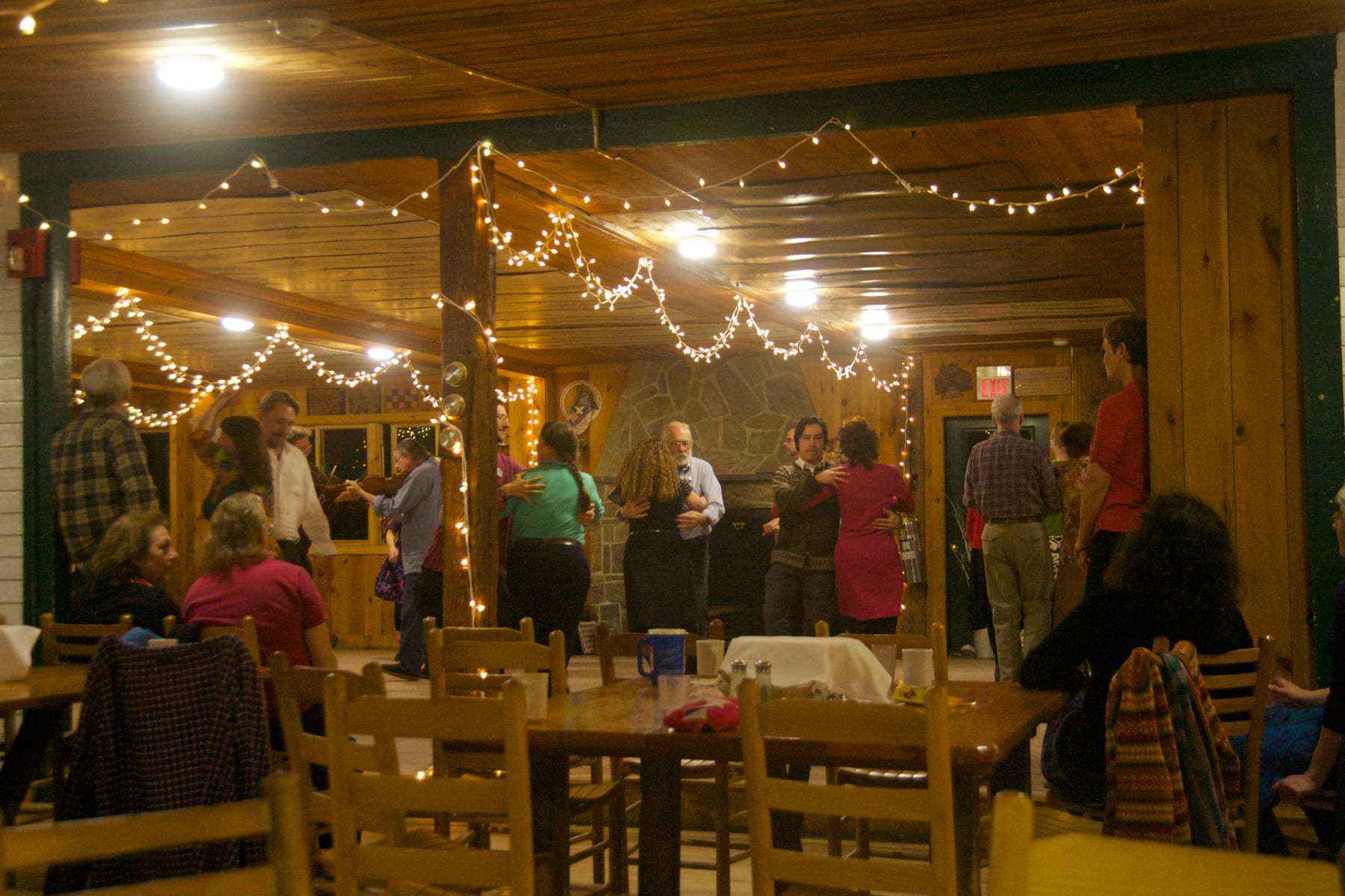 Participants dancing in a room with string lights during an indoor evening event.